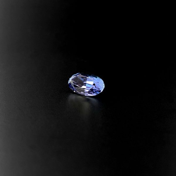 Ovaler Blau/Violetter transparenter und unbehandelter Tansanit in Scheren schliff. Der aus der Zoisit-Gruppe stammende Edelstein ist unbehandelt. Die Farbe des Steines harmonisiert zu einem warmen Goldton.