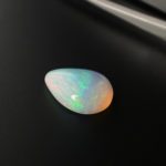 Der in Tropfen Form geschliffene milchige Edel Opal reflektiert je nach Lichteinfall ein schimmerndes buntes Farbenspiel.