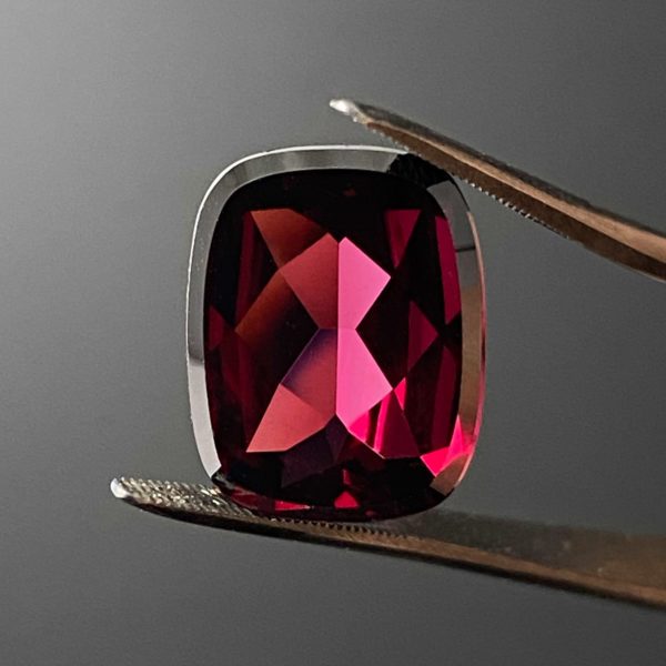 Dieser rote Edelstein ist ein Granat mit einem Schliff in Kissenform.