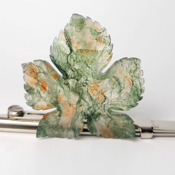 Dieser Edelstein ist ein orange grüne Moosachat graviert in einer Blätterform.